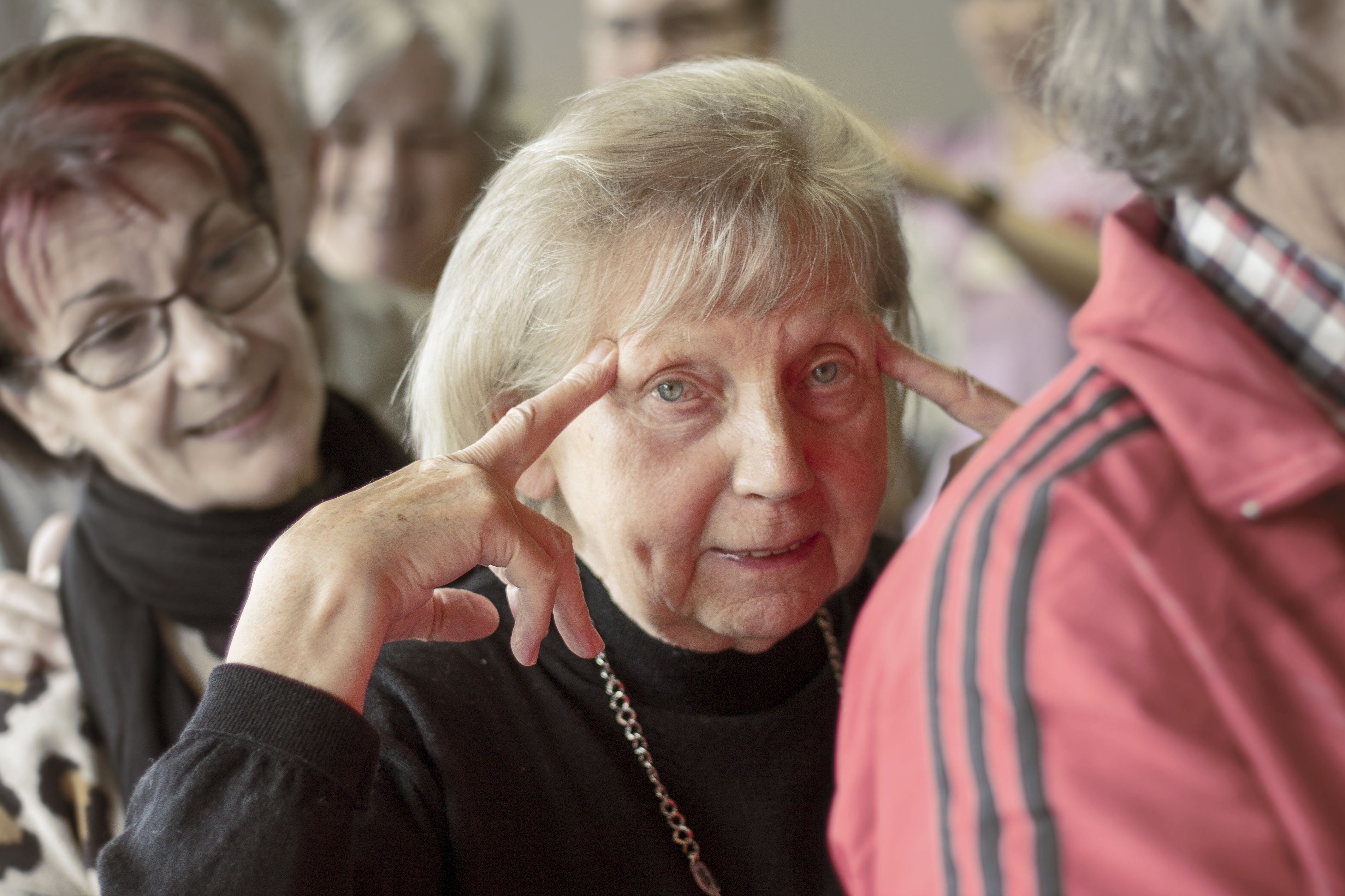 Ältere Frau fasst sich mit beiden Zeigefingern an ihre Schläfen