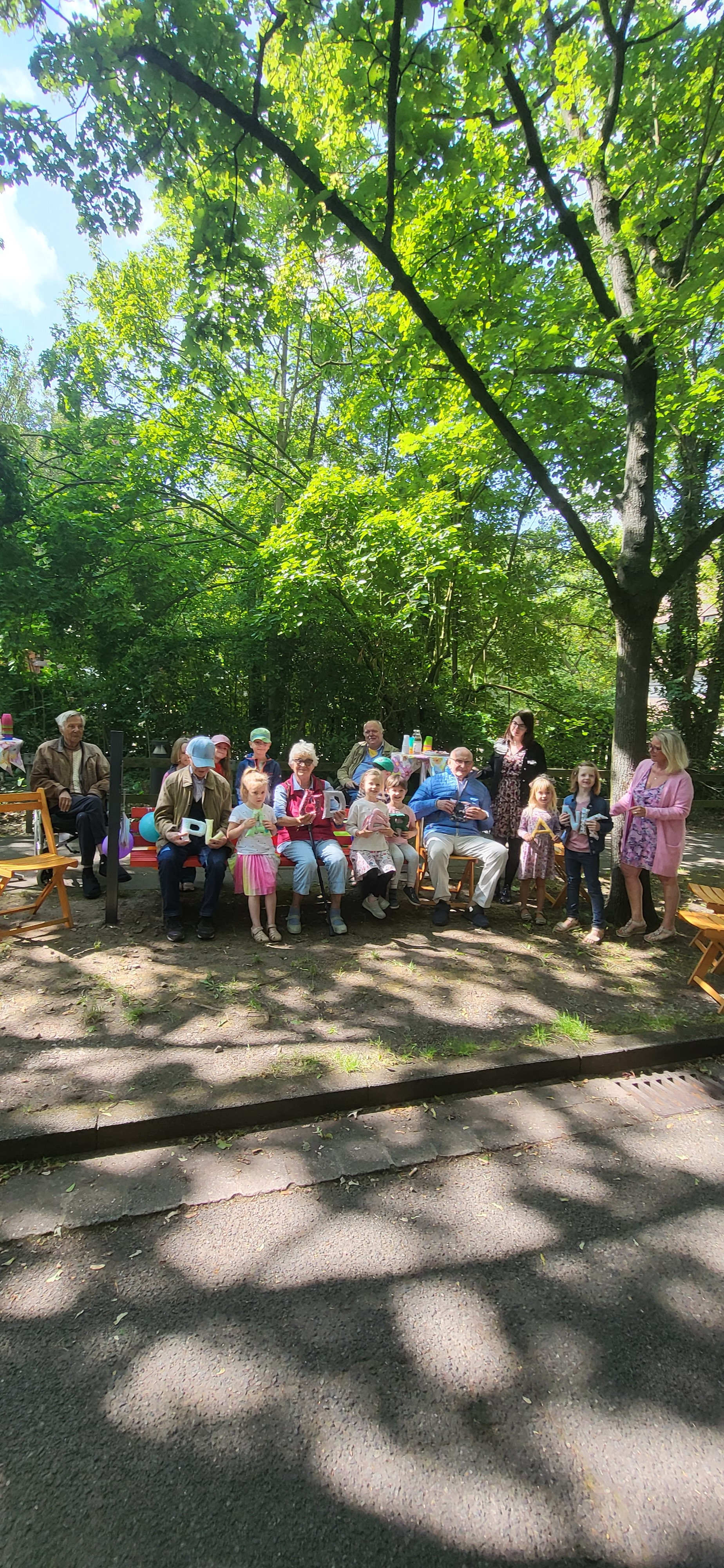 Alte Menschen und Kinder sitzen zusammen auf der Plauderbank