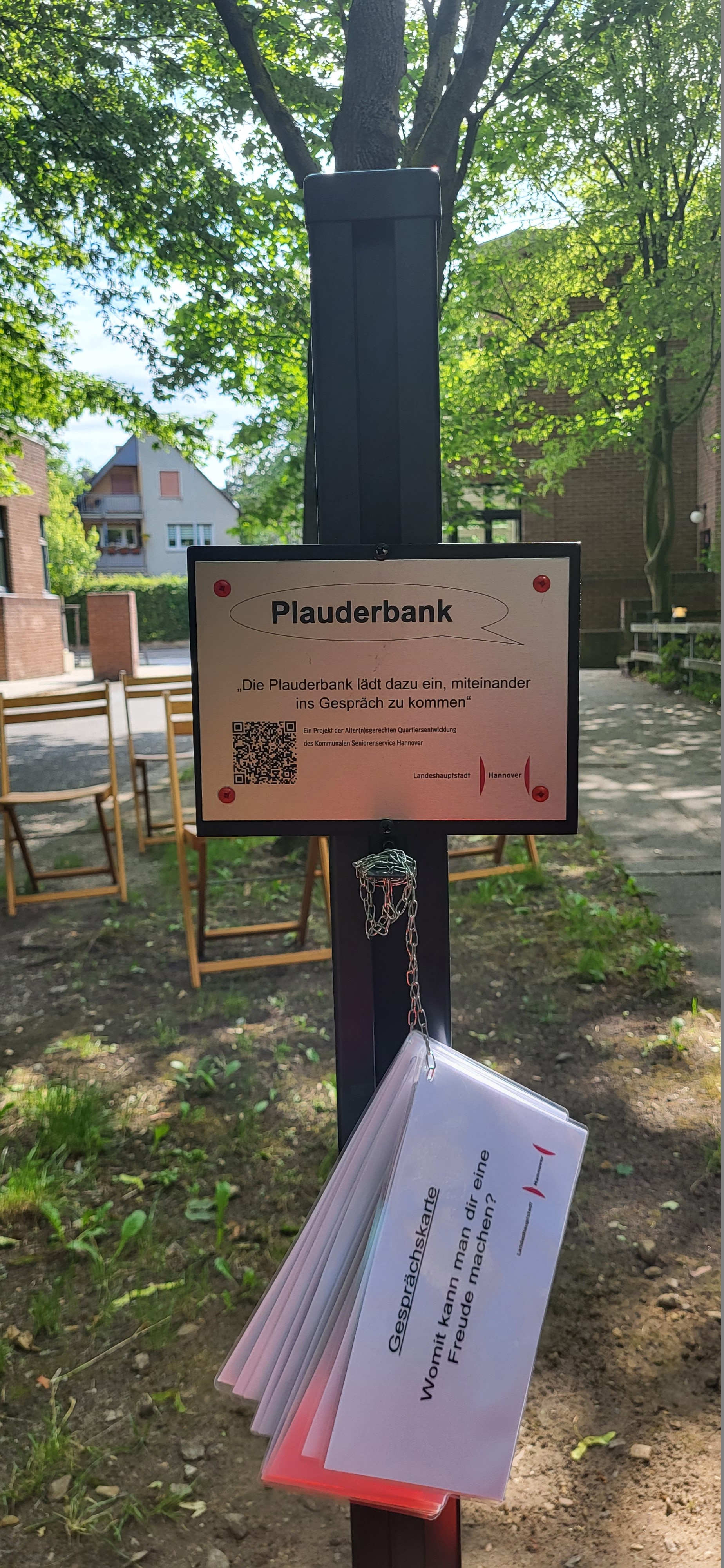 Schild für die Plauderbank mit QR Code und Zetteln zum Gesprächsanlass